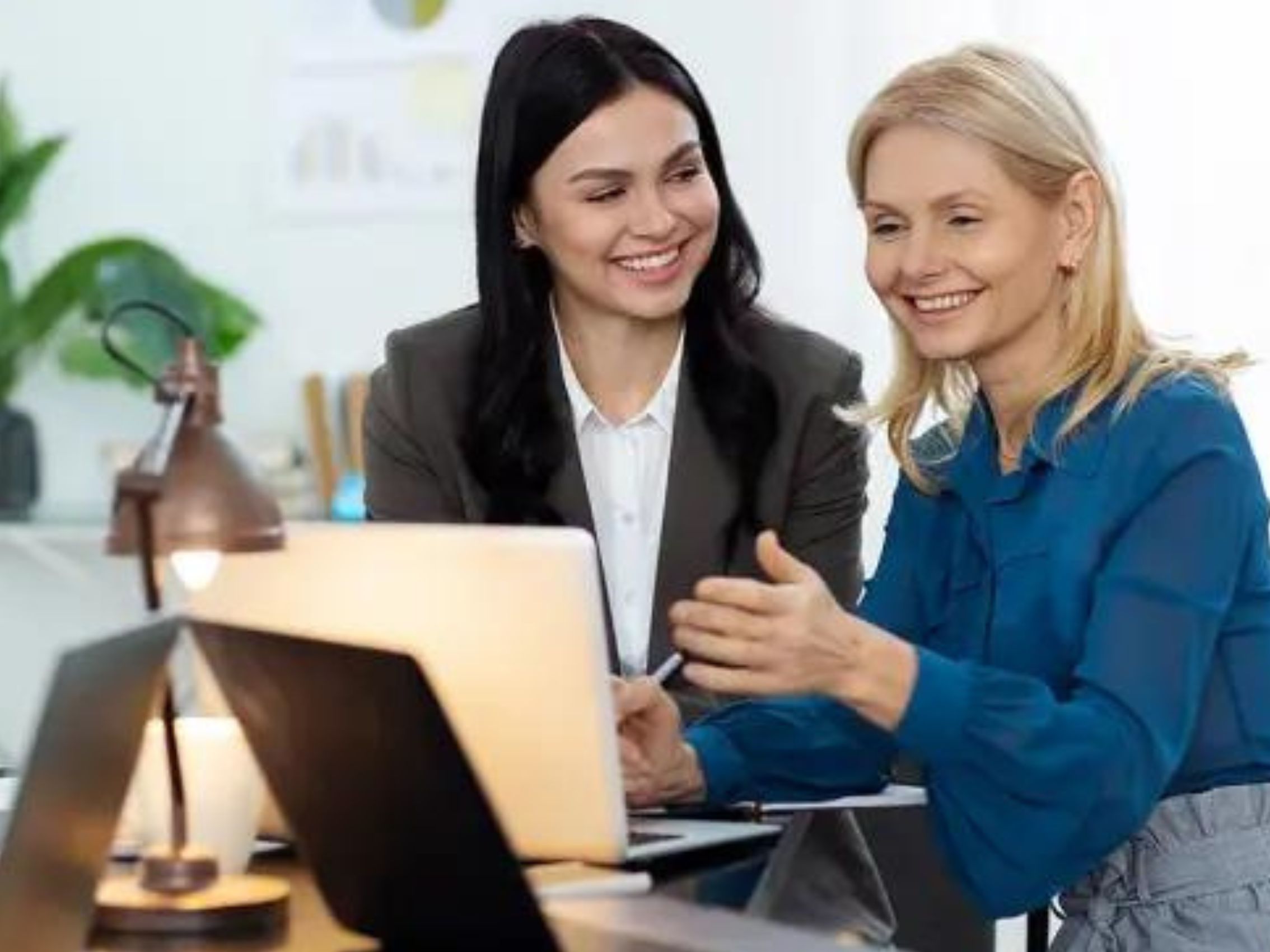 Two business women in discussion at a laptop.